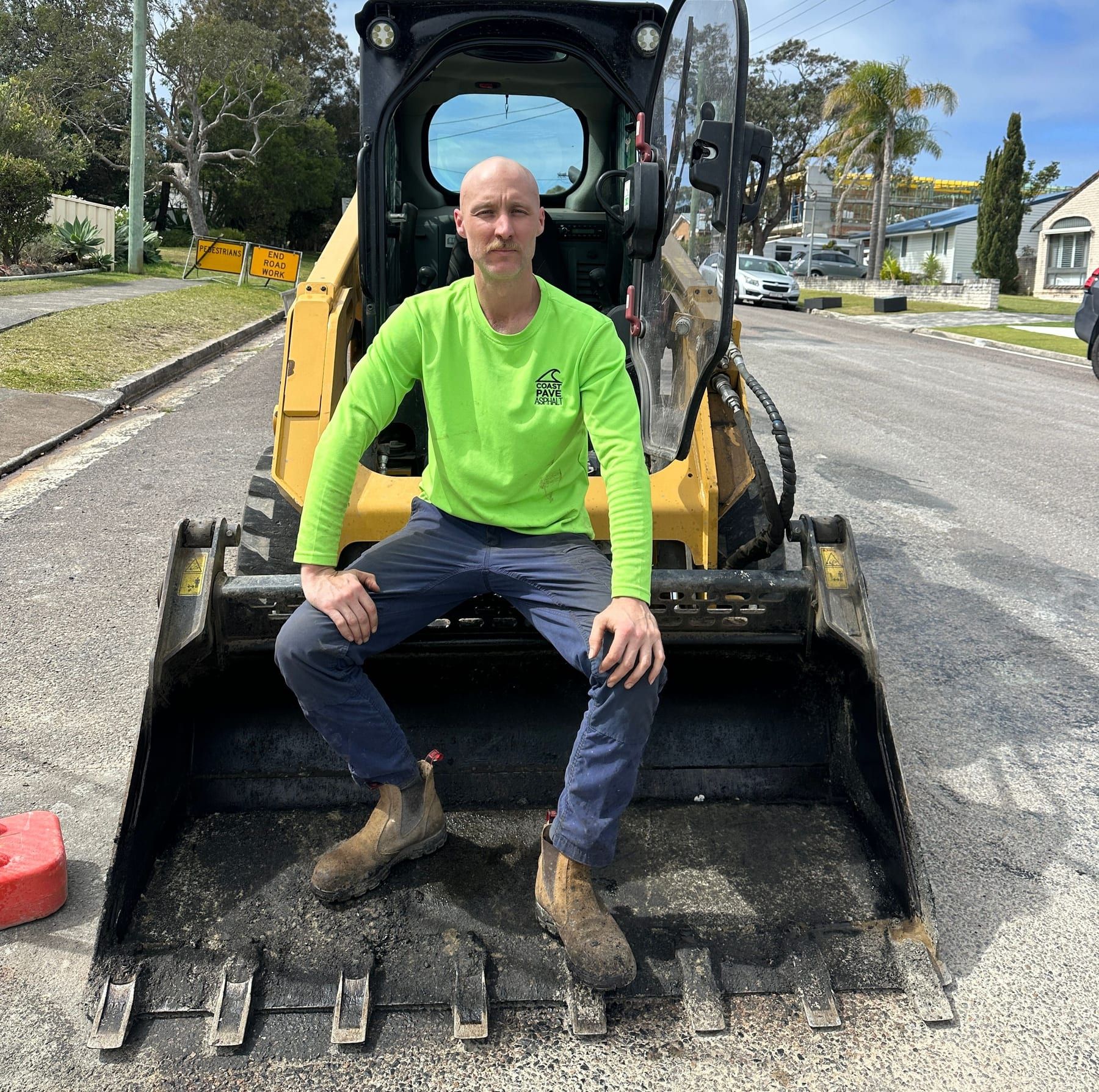 Nathan Harmond in hi-vis, operating a Bobcat skid steer on a job site